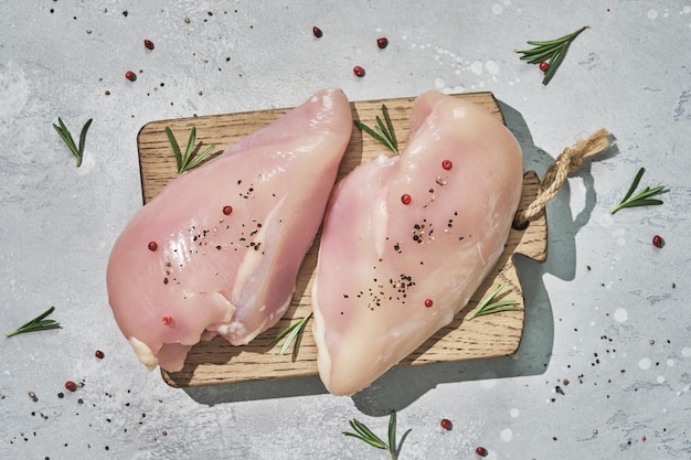 Фото Сырые куриные грудки и специи на деревянной разделочной доске