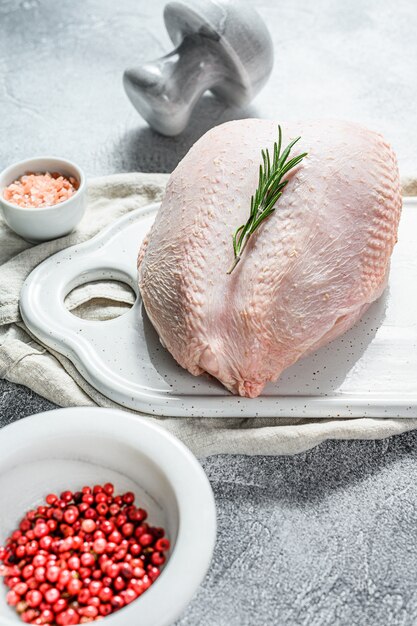 Raw chicken breasts on a white chopping board. organic farm\
bird. fresh fillet with skin. gray background