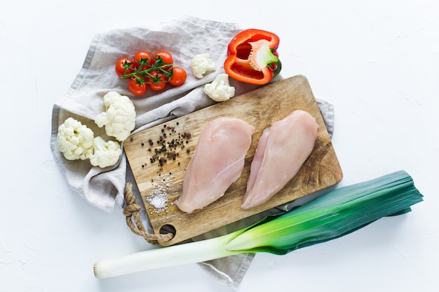 Raw chicken Breasts on a wooden chopping Board.