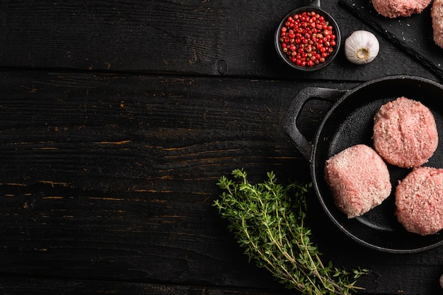 Raw chicken cutlets ground meat patty on black wooden table background top view flat lay with copy space for text