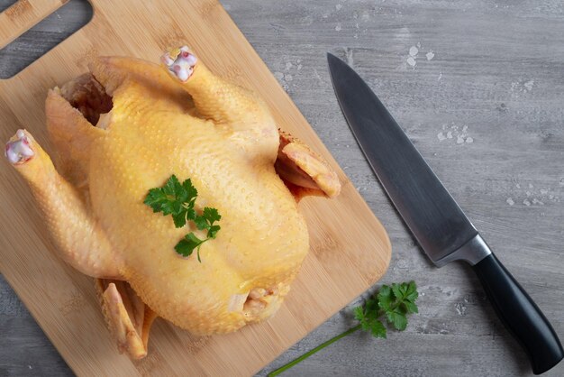 Сырая курица на разделочной доске и нож