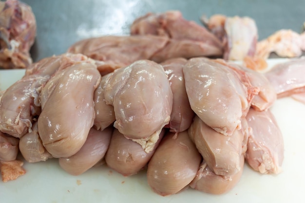 Raw chicken on a cutting board with one being cut into pieces.