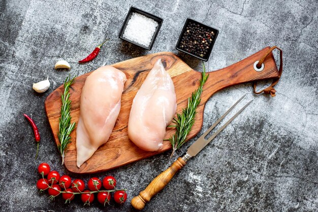 Photo raw chicken on a cutting board with spices and herbs