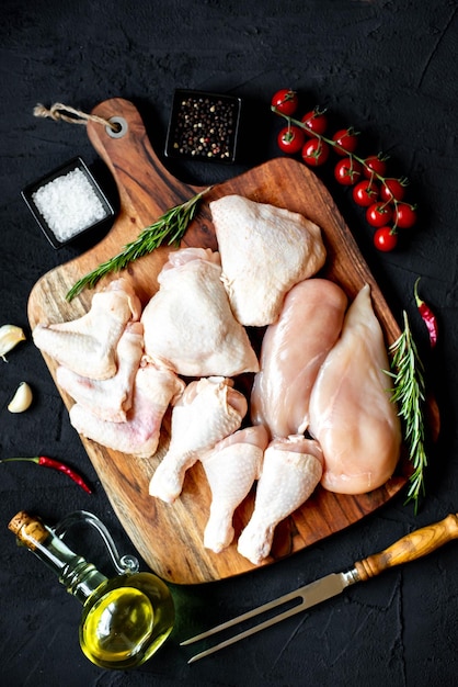 Raw chicken on a cutting board with spices and herbs.