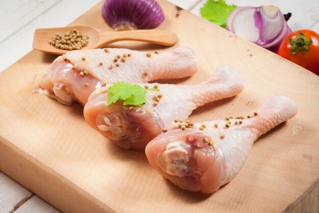 Raw Chicken Drumsticks met peterselie en peper op snijplank