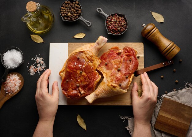 Foto bastoni di pollo crudo conditi su una tavola di legno accompagnati da sale e peperoncino