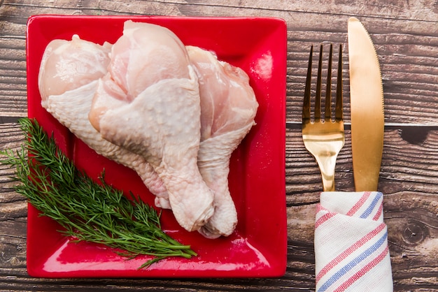 写真 生の鶏のモモ肉の皿に新鮮なディル