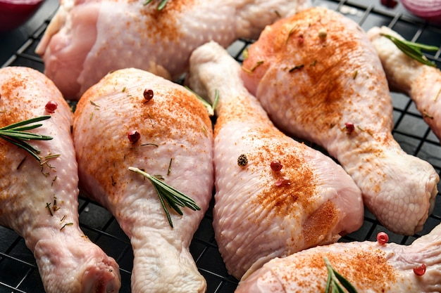 Raw chicken drumsticks with ingredients for cooking on a black stone surface