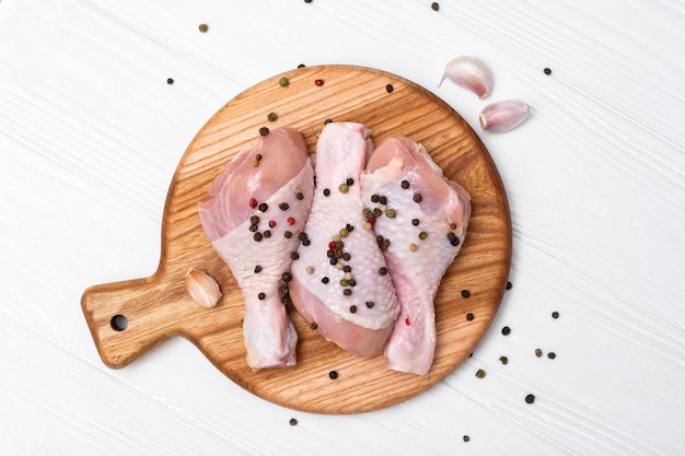 Foto bacchette di pollo crude su una tavola di legno carne di pollo fresca su un tagliere vista dall'alto dall'alto