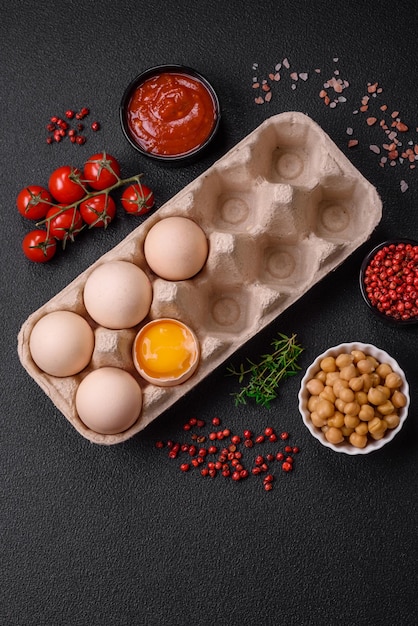 Photo raw chicken eggs in a box cherry tomatoes chickpeas spices salt and herbs