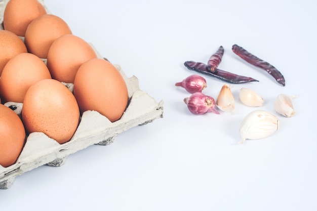 Raw chicken eggs in egg box on white background.