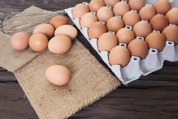  raw chicken eggs on sack cloth fabric on old brown wooden