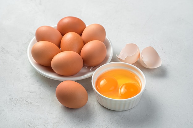 Сырые куриные яйца и два желтка на сером фоне