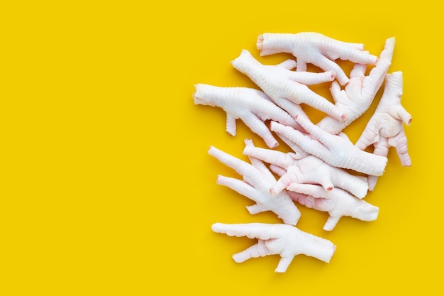 Raw chicken feet on yellow background