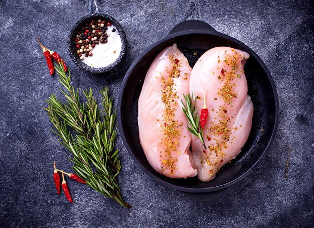 Raw chicken fillet in cast iron pan