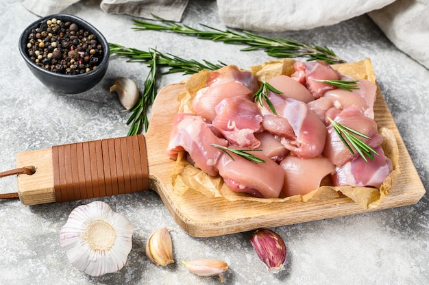 Raw chicken fillet cut into cubes with spices. Gray background. Top view