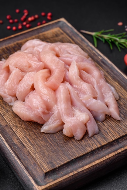 Raw chicken fillet cut into strips with spices and herbs