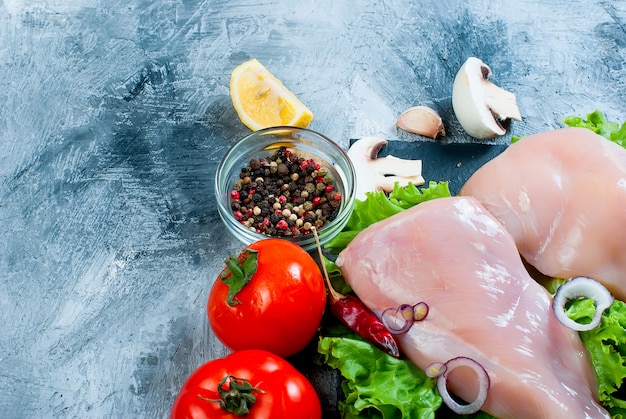 Raw chicken fillet on cutting board with spices and herbs.