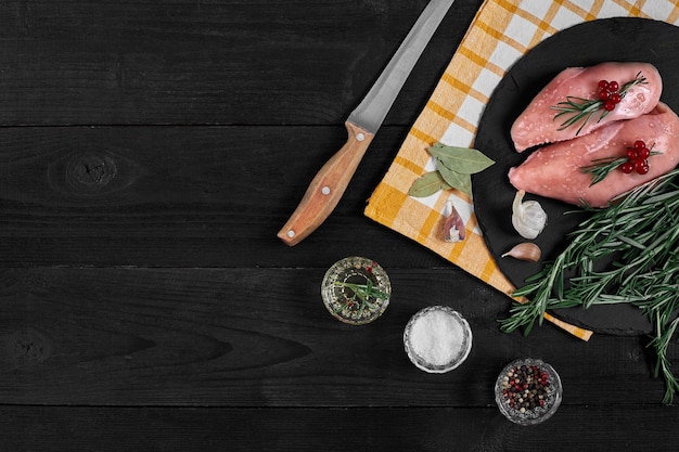 Filetto di pollo crudo con ingredienti da cucina su tavola di ardesia nera sfondo alimentare vista dall'alto spazio per la copia natura morta piatto