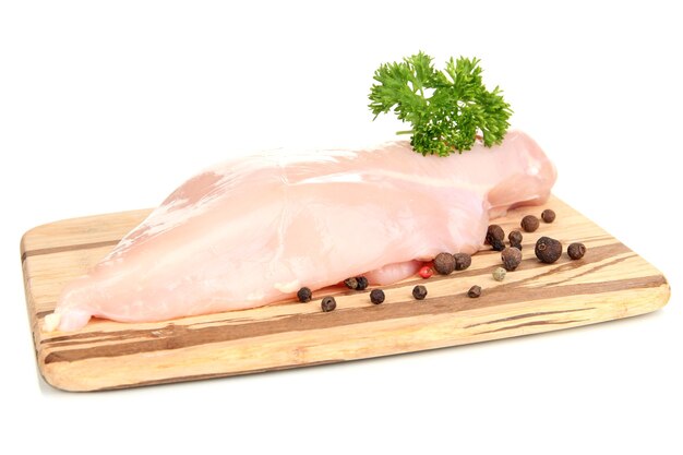 Raw chicken fillets on wooden board, on white