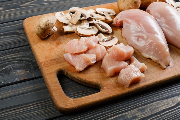 Raw chicken fillets on wooden cutting board, top view