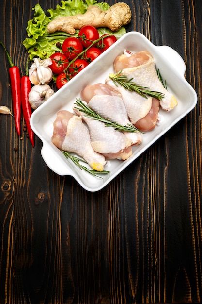 Raw chicken legs in baking dish on a wooden table