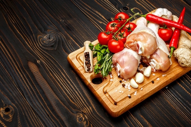 Coscie di pollo crude nel piatto di cottura su una tavola di legno