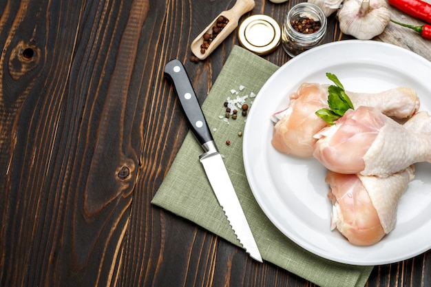 Raw chicken legs in baking dish on a wooden table