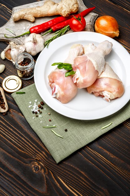 Raw chicken legs in baking dish on a wooden table