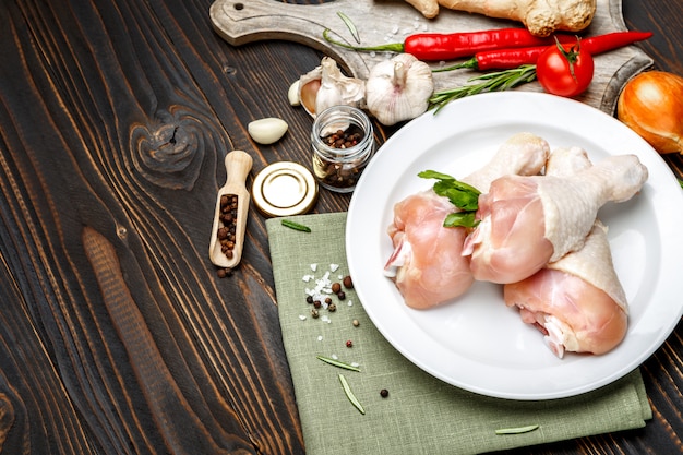 Raw chicken legs in baking dish on a wooden table