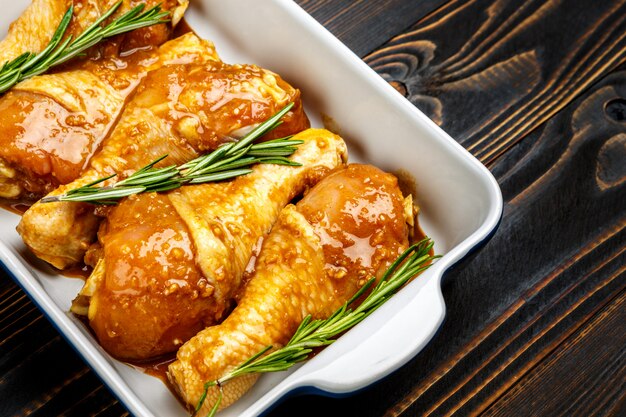 Raw chicken legs in baking dish on a wooden table