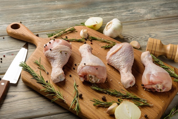 Photo raw chicken legs on a cutting board close-up. chicken meat with spices on a cutting board.