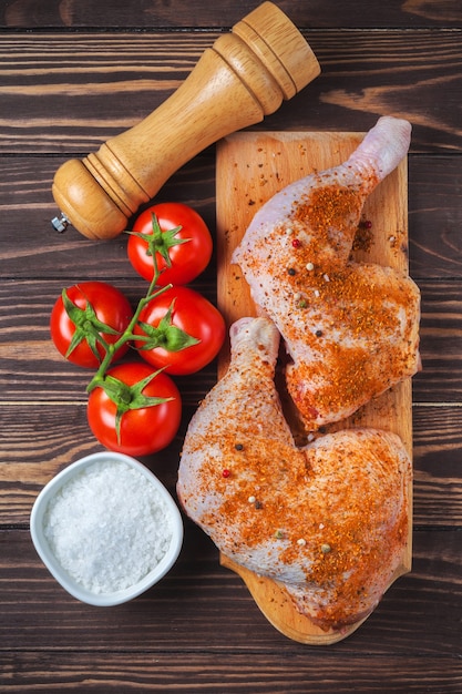 Raw chicken legs on a cutting board on a wooden table