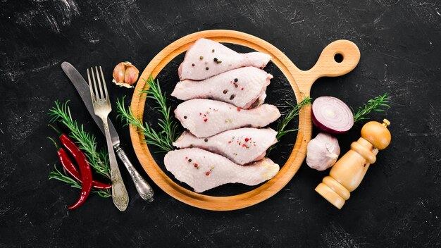 Raw chicken legs and spices and herbs Barbecue On a black stone background Top view Free copy space