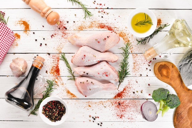 Raw chicken legs and spices and herbs Barbecue On a white wooden background Top view Free copy space