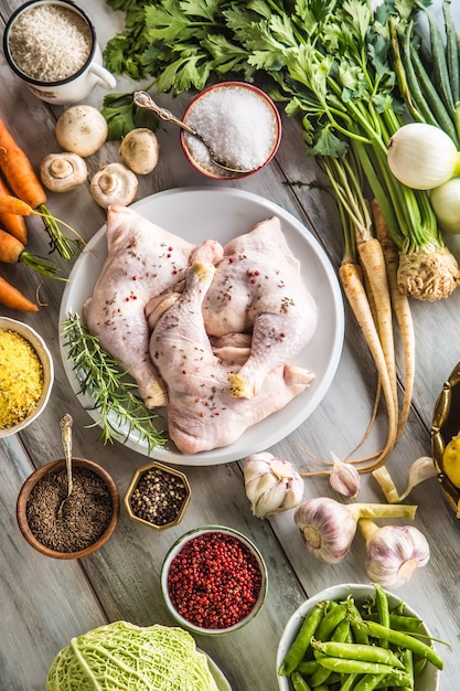 Raw chicken legs with assortment spices and vegetables.