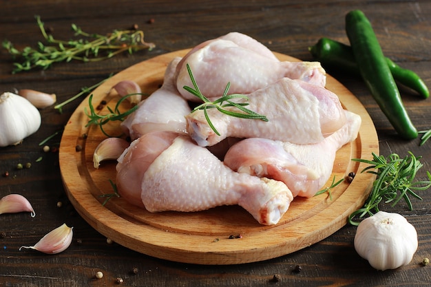 Raw chicken legs with spices on a board on a wooden table