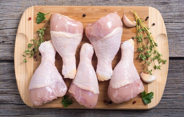 Raw chicken legs with spices on cutting board