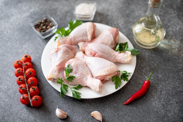 Cosce di pollo crudo con spezie su uno sfondo di pietra