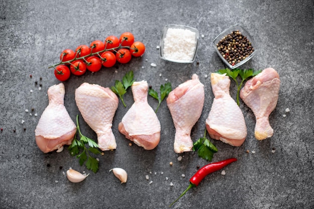 raw chicken legs with spices on a stone background