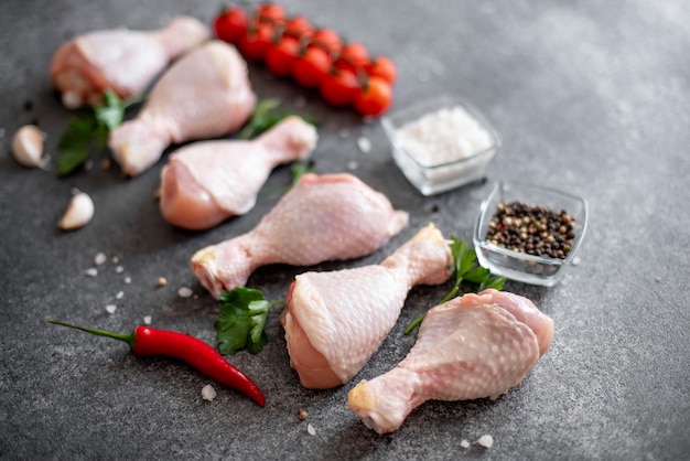 raw chicken legs with spices on a stone background