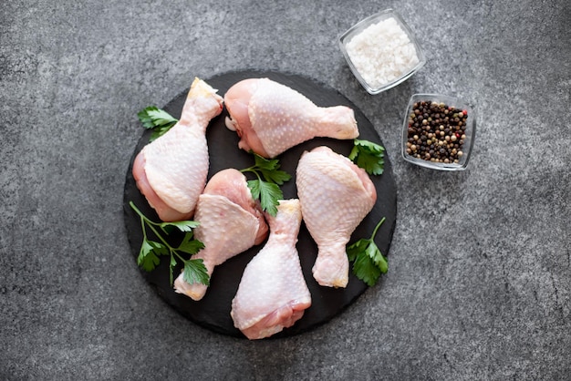 raw chicken legs with spices on a stone background