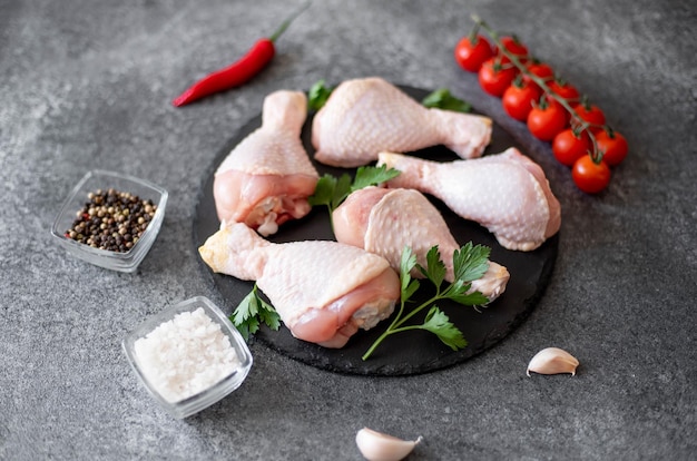 raw chicken legs with spices on a stone background