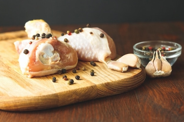 Raw chicken legs with spices on a wooden background