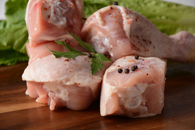 Raw chicken legs with spices on wooden board