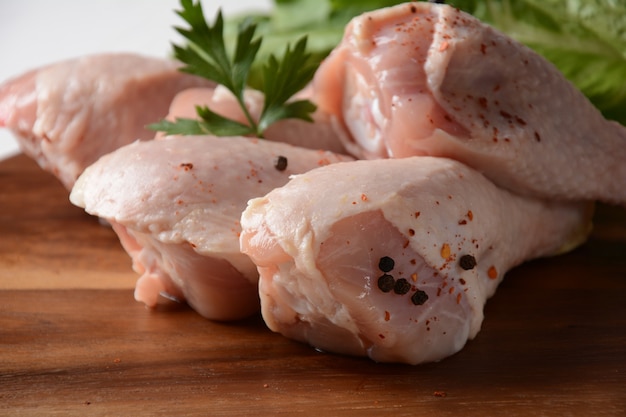 Raw chicken legs with spices on wooden board