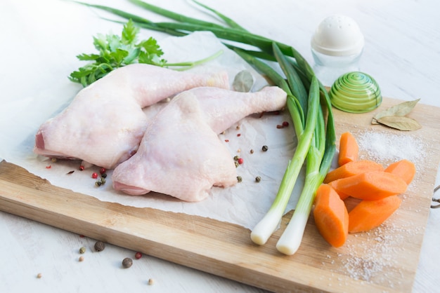 Raw chicken legs with vegetables and spices.