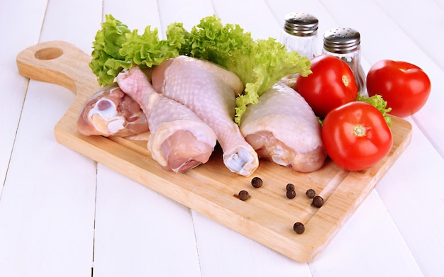 Raw chicken legs on wooden board close up