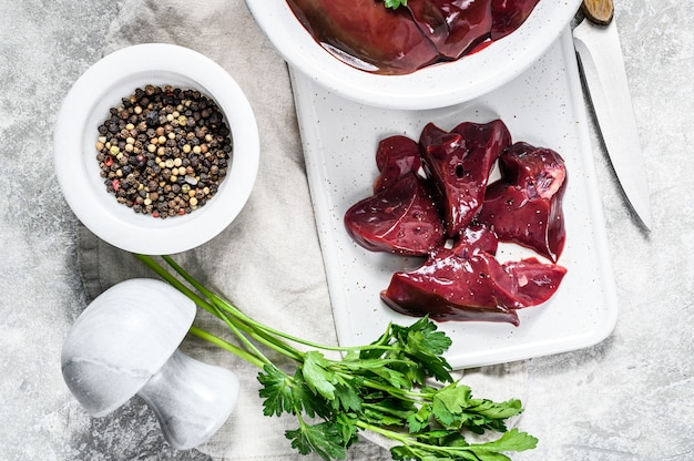 Raw chicken liver in a bowl. Gray background. Top view