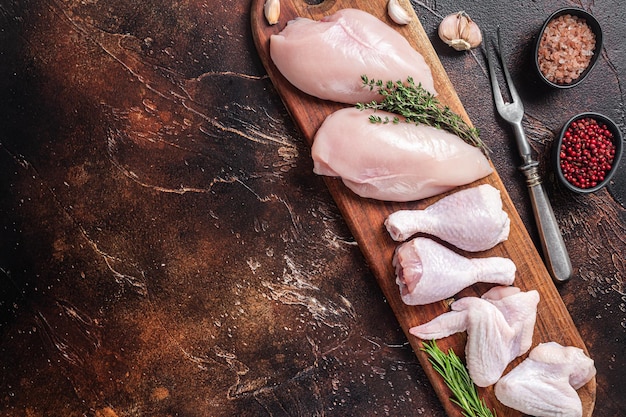 Raw chicken meat assortment of parts drumstick breast fillet wings thigh with spices Dark background Top view Copy space